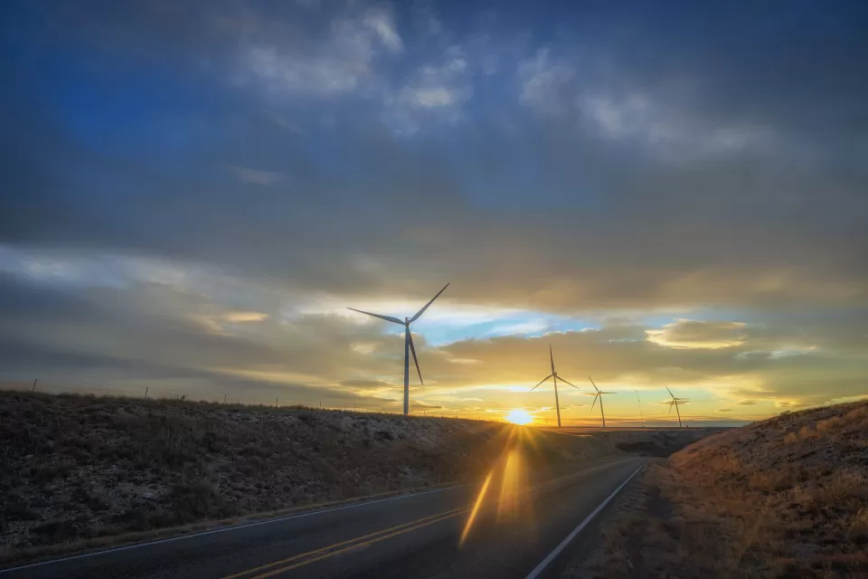 Wind turbines sillhouetted against a sunset sky along roadway in New Mexico